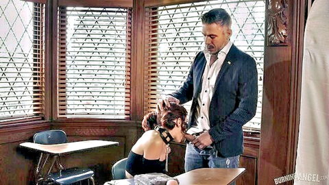 Grey-haired man in suit grabs brunette teen's pigtails bending her over classroom desk unzipping pants