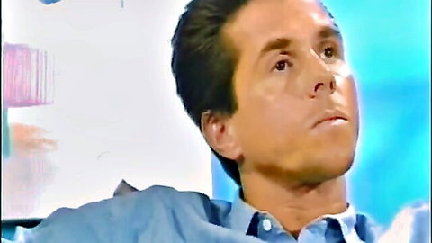 PJ Sparxx on the couch with dark-haired man in blue shirt, thoughtful gaze
