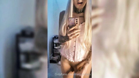 Miss Jezebel standing in pink corset, masturbating solo