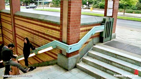 Skinny long-haired brunette exposes small pale ass on public stairs with two men grabbing her
