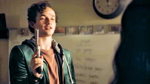 Young man with curly hair holding gun in classroom scene from Run Hide Fight