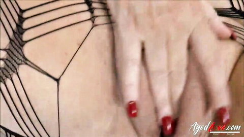 Mature woman spreads fishnet lingerie over her pussy with red nailed fingers