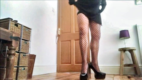 Seductive woman in fishnet stockings and mini dress posing in high heels