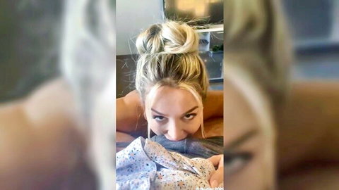 Seductive blonde babe with messy bun leans forward in open blue shirt exposing medium tits POV tease