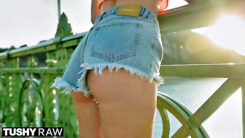 Curvy woman in ripped denim shorts teasing ass on outdoor bridge
