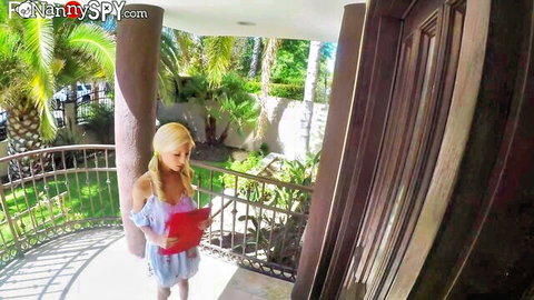 Blonde babe in low-cut off-shoulder dress showing cleavage holds red folder on sunny balcony