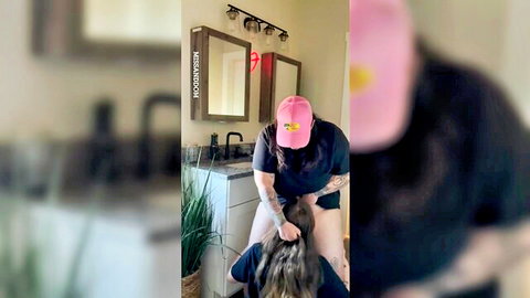 Tattooed woman in pink hat roughly pulls blonde's long hair dominating her over bathroom sink