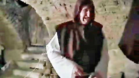 Bearded monk in brown hooded robe stands in stone dungeon ready for kinky uniform fuck