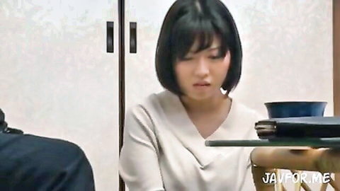 Japanese woman in white V-neck blouse looks surprised next to man at table in intense JAV scene