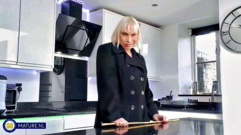 Mature blonde in black coat wielding big dildo solo in kitchen