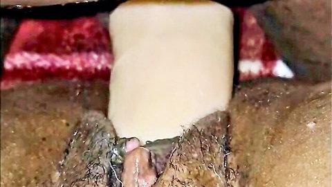 Ebony woman with bushy pussy inserts thick white dildo deep inside her wet hole closeup