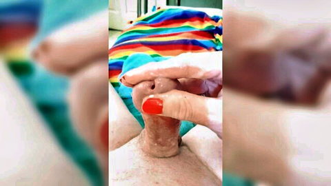 Close-up of woman's red-nailed hand teasing erect penis in climax control tease