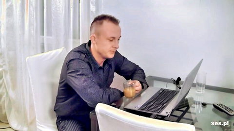 Man in dark shirt sipping tea while working on laptop at desk