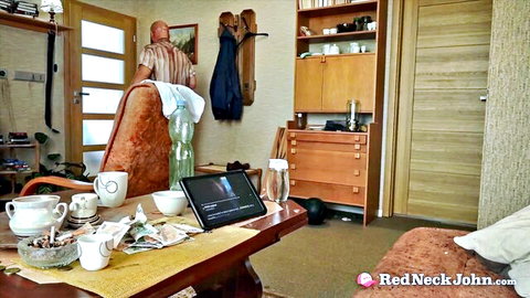 Man standing in rustic wooden kitchen with tea cups saucers tablet and shelves no nudity visible
