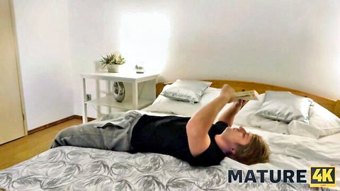 Brown-haired man lying on bed holding tablet in mature 4K gonzo scene