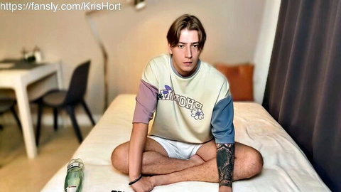 Tattooed twink in tight white shorts spreads legs on bed teasing bulge