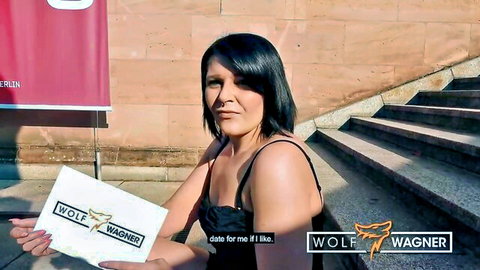 Glamorous brunette in black top holding Wolf Wagner sign outdoors