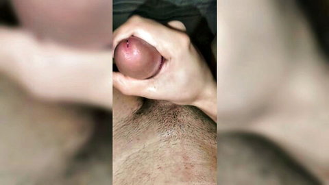 Close-up hand gripping erect penis head during intense orgasm