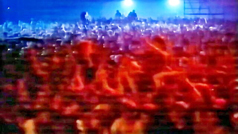 Blurry excited crowd under blue stage lights with red foreground glow at live show