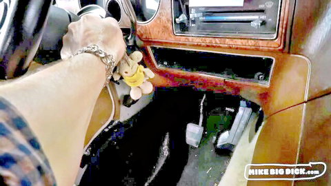 Man's hand holding yellow plush toy on car dashboard interior