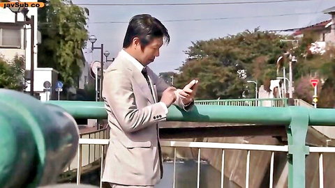 Minako Komukai JAV thumbnail: suited man checking phone on urban bridge