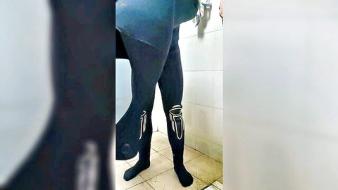 Close-up of legs in tight black scuba boots and wetsuit in steamy bathroom