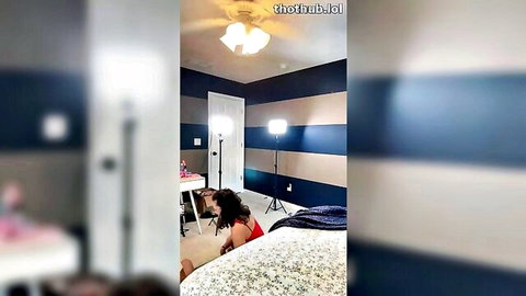PeachyPrime in red lingerie, bending over bed in sexy livestream pose