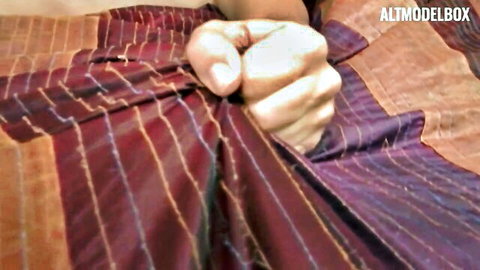 Hand gripping red striped sheets in teasing bedroom scene