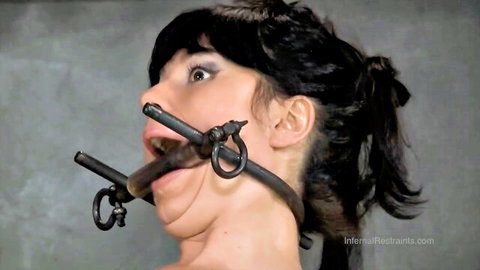 Brunette babe's mouth stretched wide by black metal ring gag in intense bondage