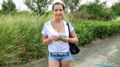 Amateur brunette in tank top and denim shorts holds cash outdoors for Public Agent pickup