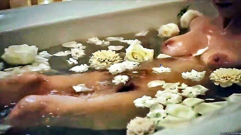 Nude MILF with big tits and erect nipples lounging in flower petal bathtub teasing wet pussy