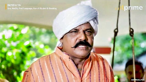 Indian man in white turban and orange striped kurta with mustache in movie scene