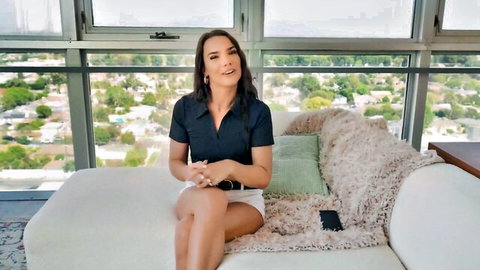 Ivy Ireland in navy polo and short white shorts, seated casually