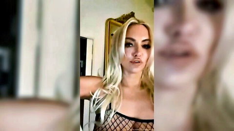 Blonde with huge tits in sheer fishnet top pouts seductively on webcam