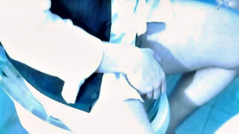Blurry closeup of man's hands gripping and spreading pale woman's nude thighs in blue pool tease