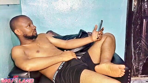 Bald black man shirtless in shorts lounging seductively