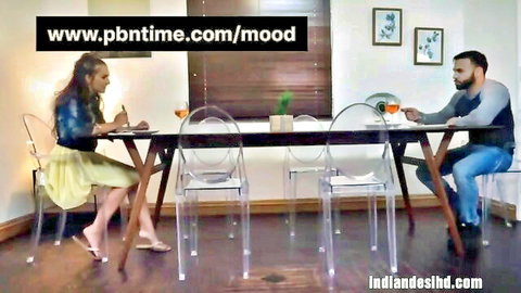 Indian couple in casual outfits at table, teasing dinner scene