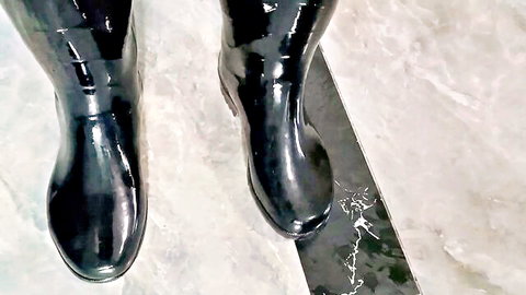 Shiny black scuba boots on furry surface in rubber fetish scene