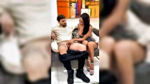 Two busty women in heels double suck a guy's hard cock with pants down on couch