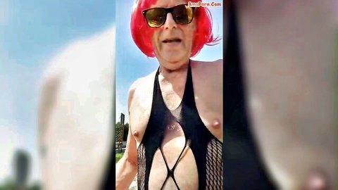 Crossdressing older man in red wig and revealing black catsuit
