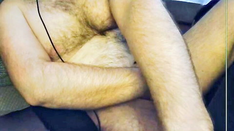Hairy Caucasian man shirtless with headphones, exposing lower body in car