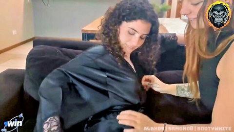 Curly-haired beauty in open satin robe teasing with tattooed friend, lesbian foreplay