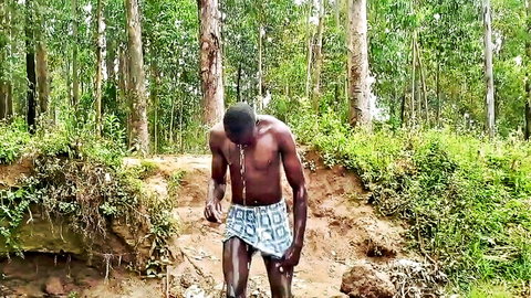 Muscular Kenyan man shirtless in forest, sweating during hot bath scene
