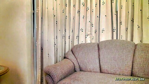 Empty beige sofa in Asian street meat hotel room with sheer curtains