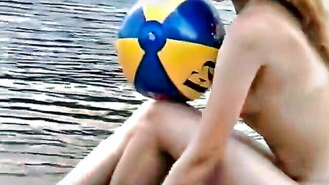 Nude blonde babe squats on beach covering pussy with yellow beach ball exposing perky tits