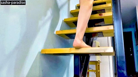 Barefoot woman stepping up wooden stairs in home interior