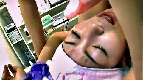 Japanese woman eyes closed mouth open as gloved hand probes with medical tool in clinic exam