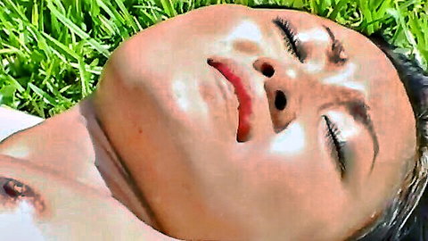 Asian teen with intense sweaty orgasm face mouth open lying on grass outdoors
