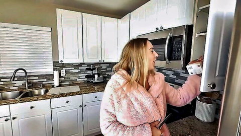 Blonde curvy step-sis in pink robe smiling in kitchen before family dinner tease