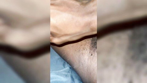 Blurry close-up of black man's groin and pubic hair in masturbation scene